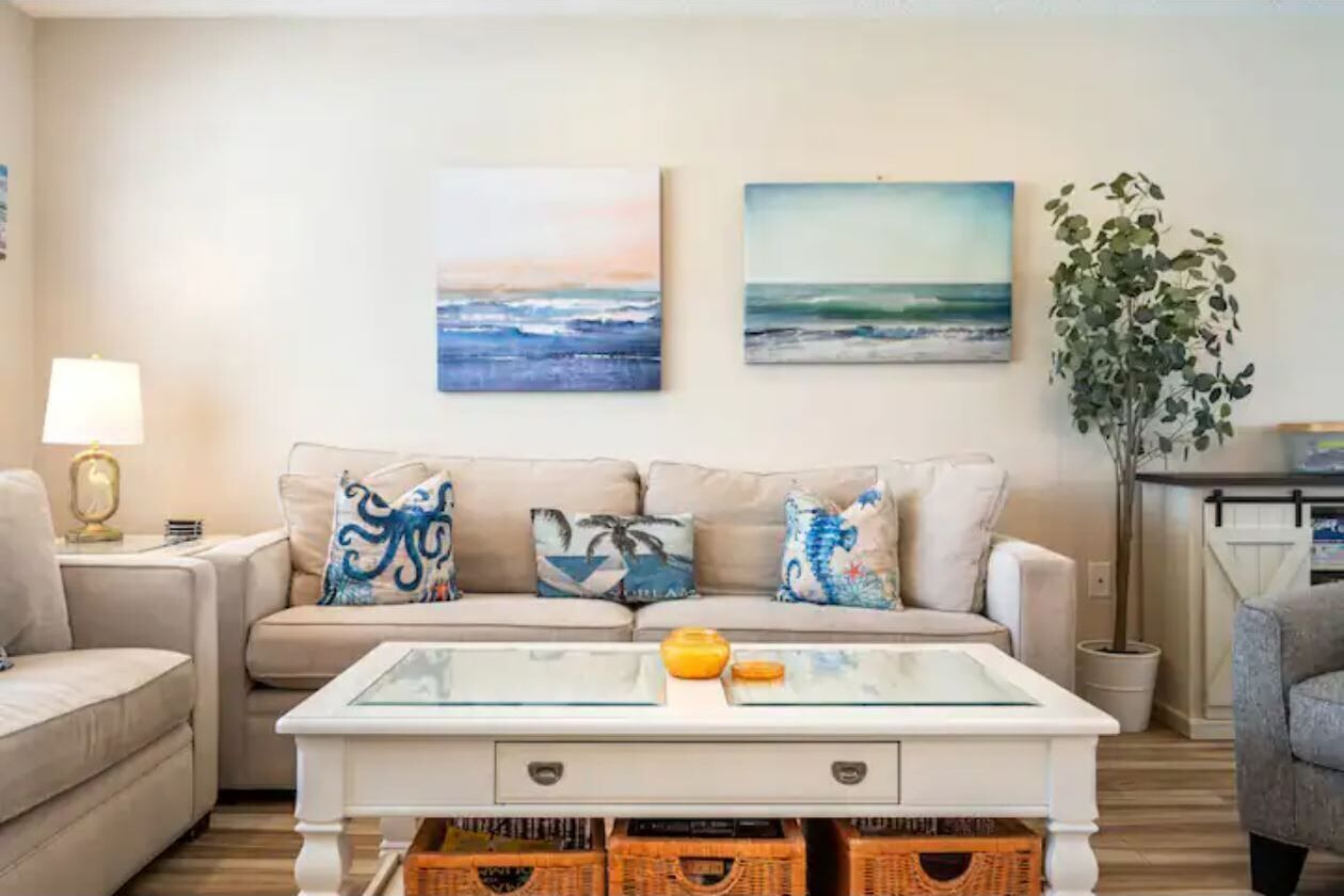 A living room with a sofa, a coffee table, and two wall-mounted paintings.