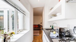 Una cocina pequeña con ventana, estufa y lavamanos.