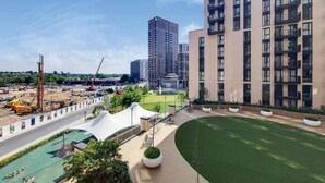 A modern residential building with a rooftop garden and a construction site in the background. - Wembley Empire Apartment - City Living (Wembley)