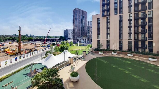 A modern residential building with a rooftop garden and a construction site in the background. - Wembley Empire Apartment - City Living (Wembley)