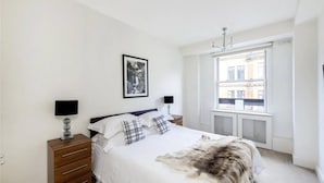 A bedroom with a bed, a window, a wall-mounted TV, and a framed picture. - Wembley Empire Apartment - City Living (Wembley)