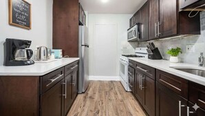 Una cocina moderna con armarios de madera oscura, electrodomésticos de acero inoxidable y una encimera blanca.