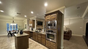 A modern kitchen with granite countertops, wooden cabinets, and stainless steel appliances. - Fountain Hills Grandeur (Lubbock)
