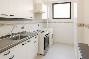 A compact kitchen with a sink, stove, and washing machine.