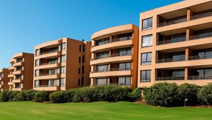 Una fila di moderni edifici residenziali a più piani con balconi, immersi in prati curati.