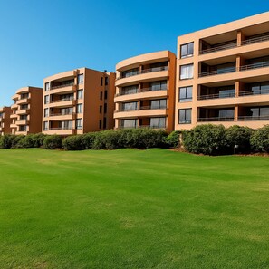 Uma fileira de edifícios residenciais modernos, com vários andares e varandas, cercada por gramados bem cuidados.