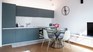Une cuisine moderne avec des meubles de couleur grise, une table de salle à manger ronde avec des chaises et une horloge murale décorative.