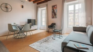 Un salon moderne comprenant un coin repas, un canapé, un téléviseur et un tableau accroché au mur.