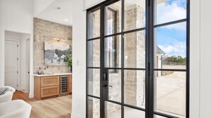 Una cocina moderna con protector de encimera de piedra, armarios de madera y un amplio ventanal corredera que da a un patio exterior.