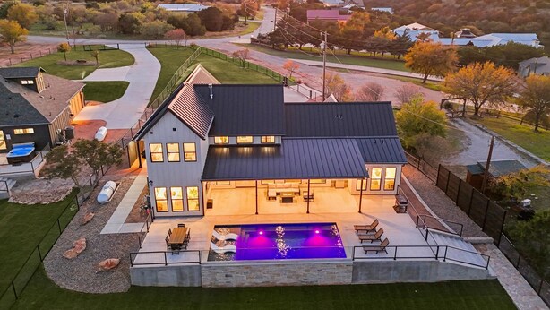 Una casa moderna con un amplio patio trasero, piscina y césped cuidado.