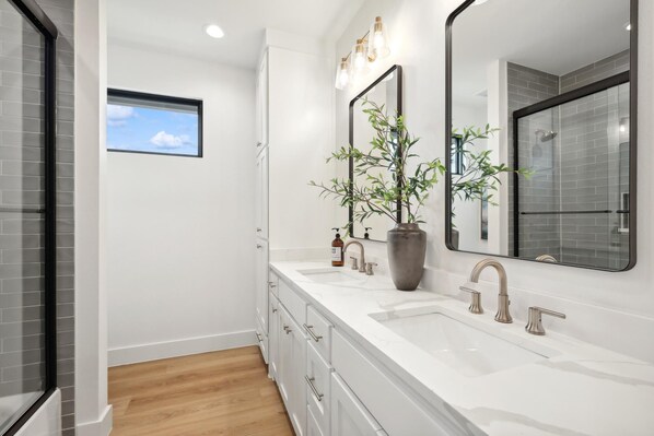 Un baño moderno con un espejo grande, dos lavamanos y una planta en maceta.