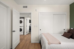 A bedroom with a bed, a washing machine, and a door leading to a laundry room. - King Bed, EV Charger, Pet-Friendly, Balcony, Near Airport & Beaches (San Diego)