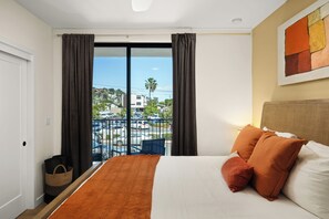 Une chambre d’hôtel avec un lit, une vue sur un parking et un balcon.
