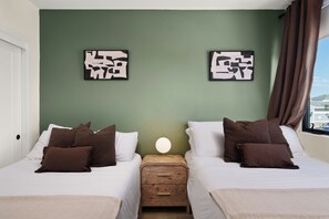 Une chambre d’hôtel avec deux lits, une table de chevet avec une lampe et des œuvres d’art accrochées au mur.