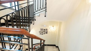 Un escalier avec une main courante en bois et des balustres en métal, menant à l’étage supérieur.