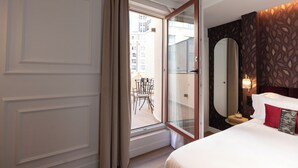 Une chambre d’hôtel avec un grand lit, une table de chevet, un miroir et une vue sur le balcon extérieur.