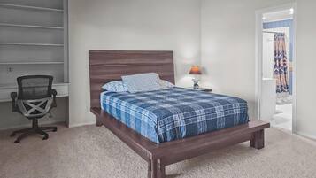 Une chambre à coucher avec un lit en bois, un bureau avec une chaise, une lampe et une porte donnant sur une autre pièce.