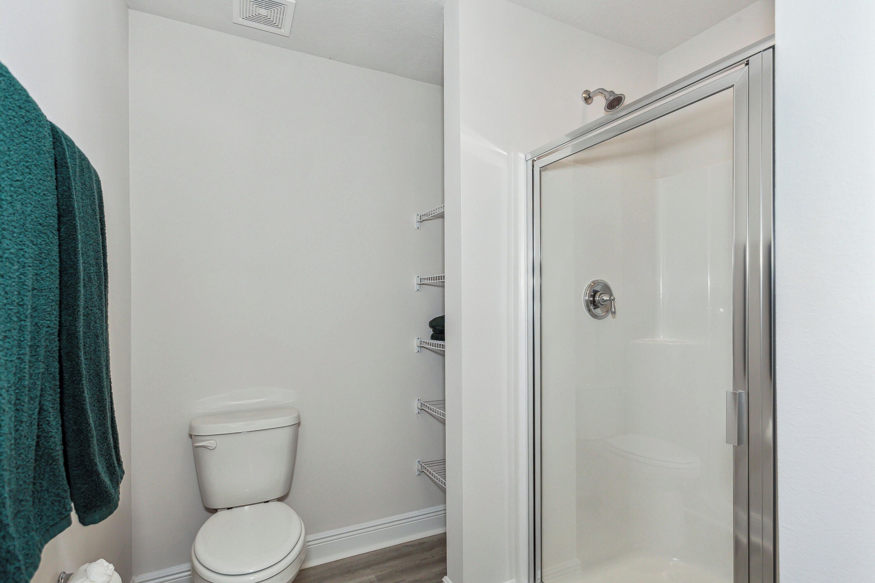 A bathroom with a toilet, a shower with a glass door, and a towel rack.