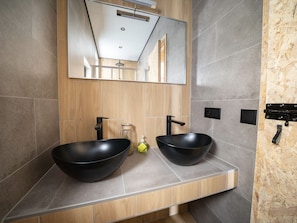 A modern bathroom with two black vessel sinks, a wooden vanity, and a large mirror above the sinks.