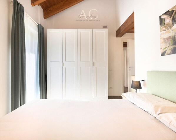 A bedroom with a large bed, a wardrobe, and a painting on the wall. - Sesto Senso in Ponte di Legno (Ponte di Legno)