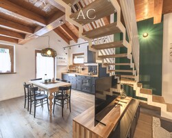 Una cocina moderna con vigas de madera, un comedor con mesa y sillas de madera, y una escalera de diseño único.