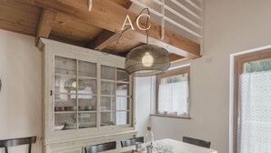 Un comedor con una mesa de madera, sillas, un aparador de vidrio y una lámpara colgante.