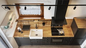 Una cocina moderna con estufa integrada, lavamanos y muebles de color negro.