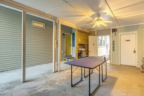 Una habitación con mesa de ping pong, ventilador de techo y una puerta con cartel de 'Welcome'.