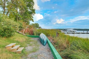 A pathway leading to a dock with a boat, surrounded by greenery and a clear sky. - Potomac River Getaway: Walk to Marina! (King George)