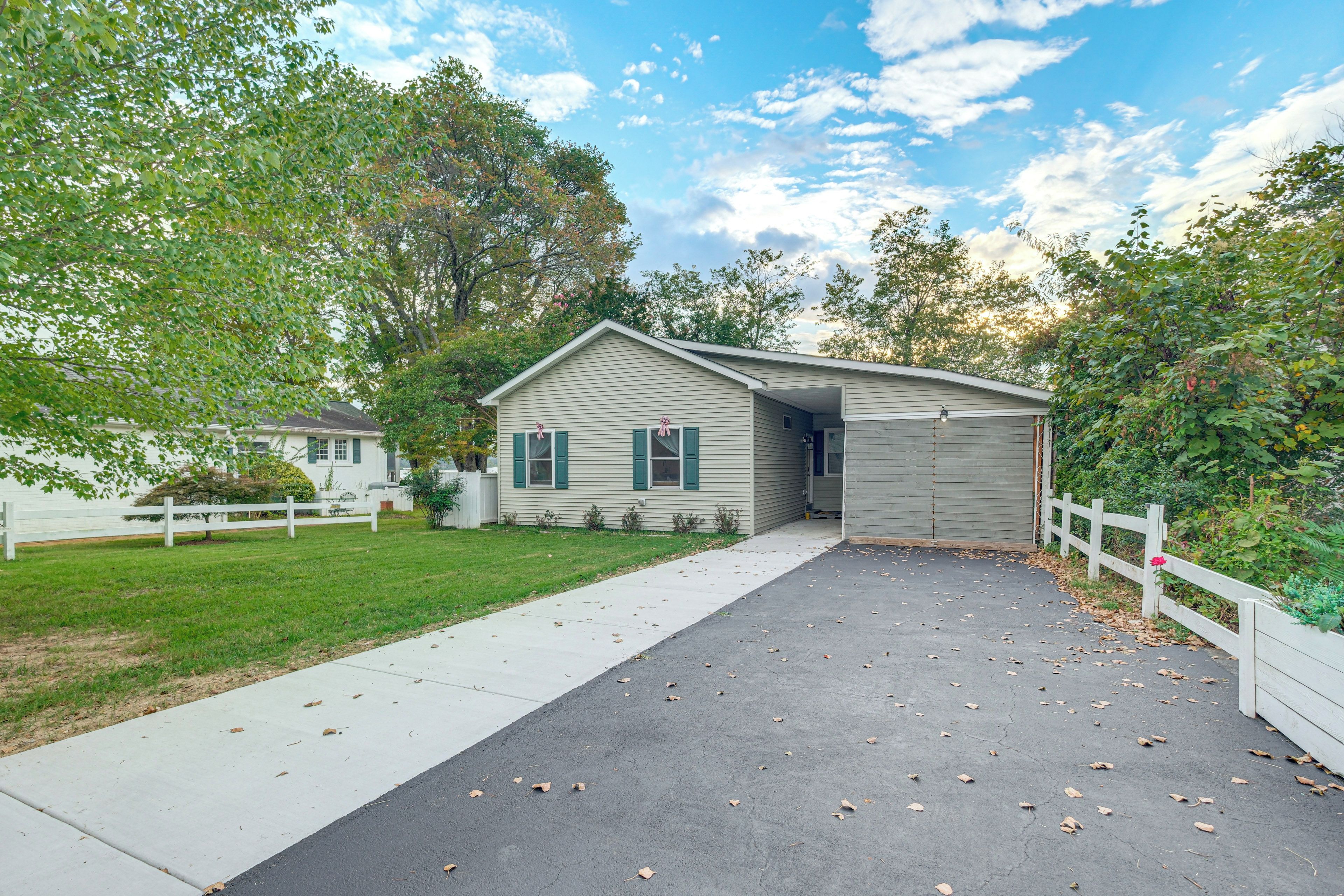 A single-story house with a front porch, a driveway, and a white picket fence.
