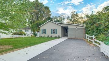 A single-story house with a front porch, a driveway, and a white picket fence.