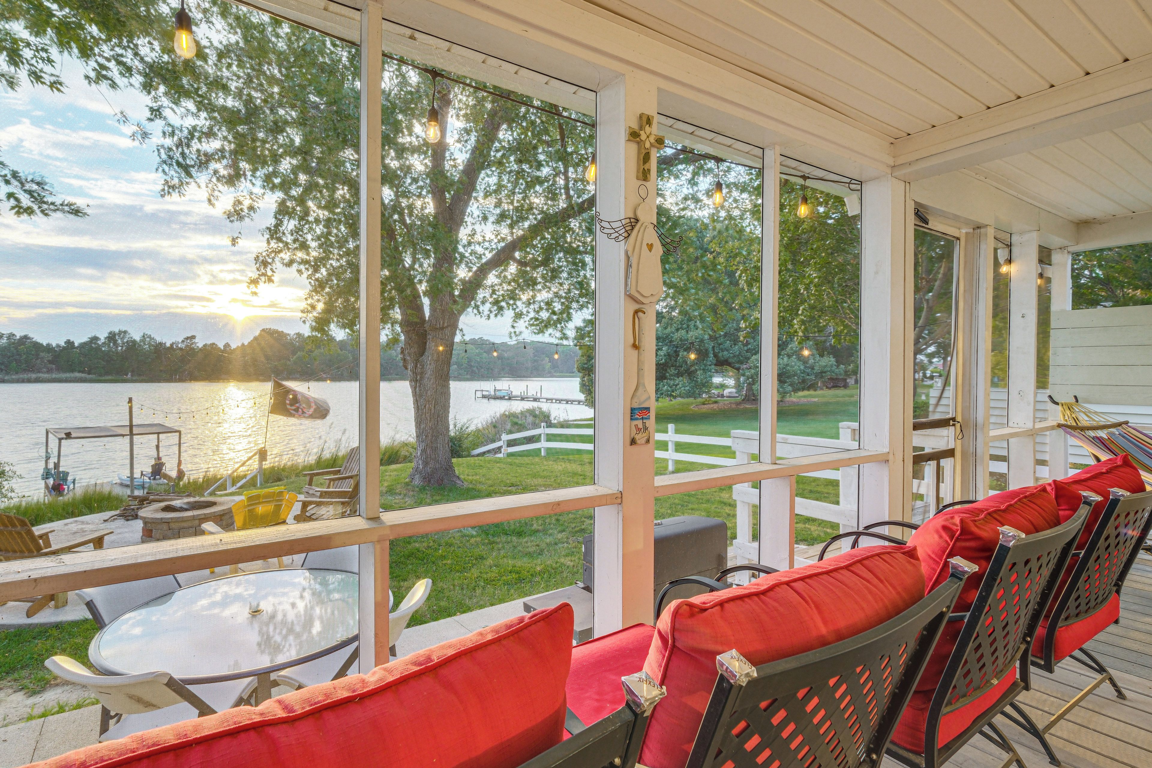 A covered outdoor seating area with a view of a lake and dock.