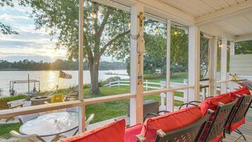 A covered outdoor seating area with a view of a lake and dock.