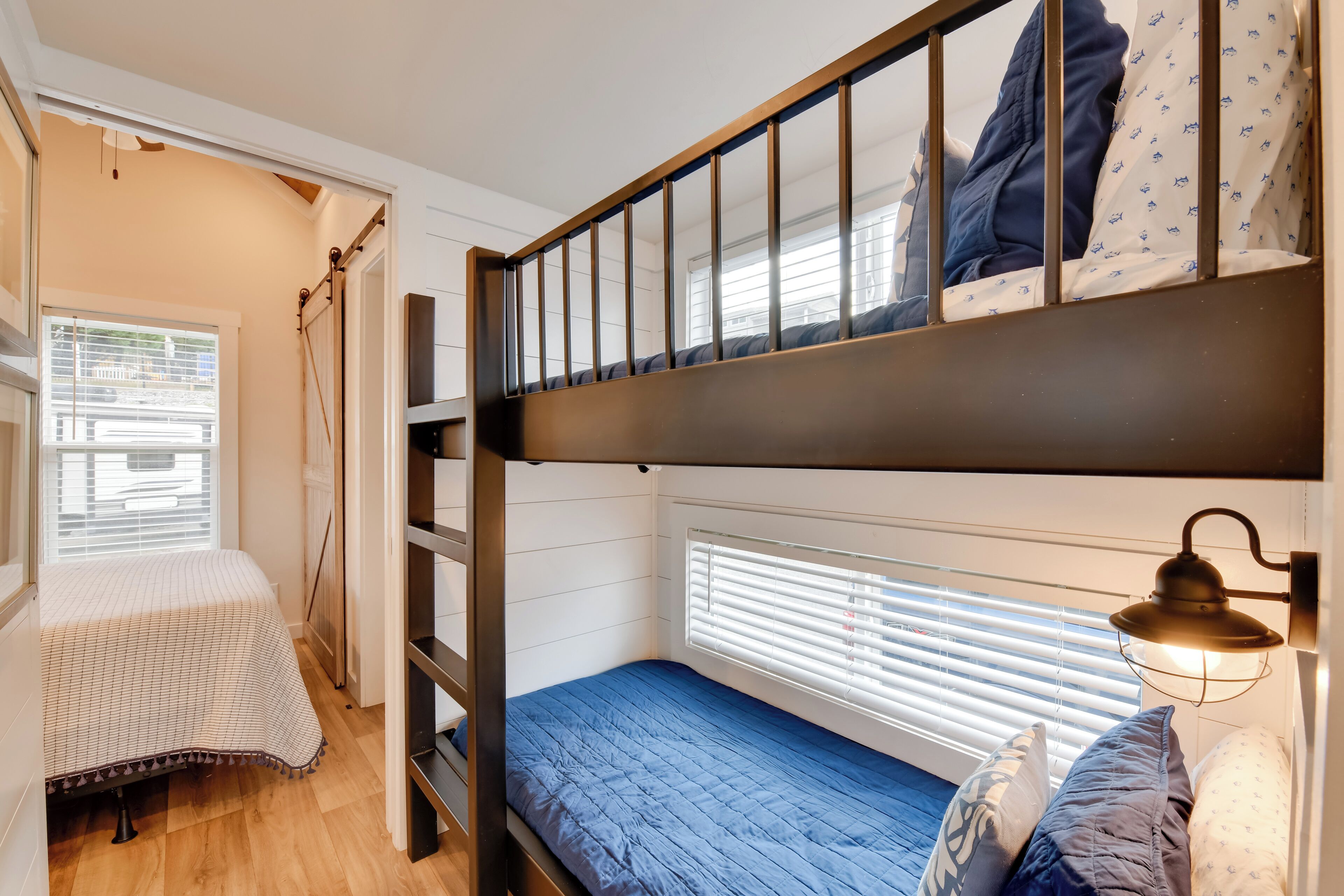 Habitación con literas, una ventana, una lámpara de noche y un escritorio pequeño.