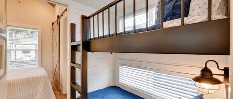 Habitación con literas, una ventana, una lámpara de noche y un escritorio pequeño.