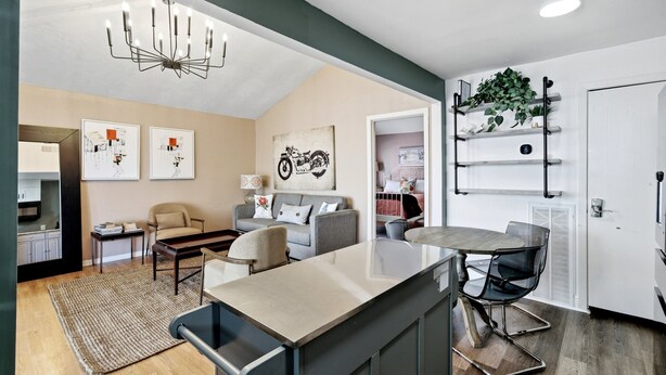 Un salon moderne comprenant un coin repas, un lustre et une plante décorative fixée au mur.