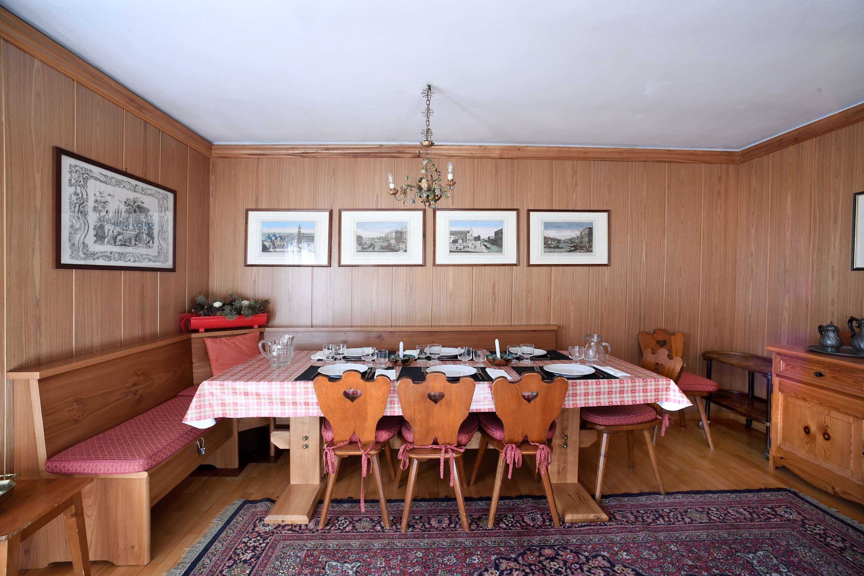 Comedor con banca de madera, una mesa dispuesta para cuatro personas y una araña.