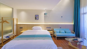 Ein Hotelzimmer mit einem Bett, einer Sitzecke inklusive Sofa, einem kleinen Tisch und einer Hängelampe.
