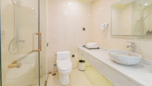 Ein modernes Badezimmer mit einer in Glas eingefassten Dusche, einer weißen Toilette und einem großzügigen Waschbecken mit Marmorplatte.