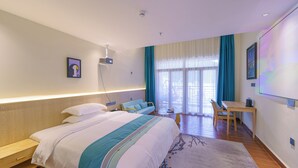 Ein Hotelzimmer mit einem großen Bett, einem Schreibtisch und einem Stuhl. Ein Fenster mit Vorhängen bietet einen Blick nach außen.