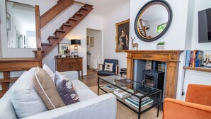 A living room with a staircase, a fireplace, a sofa, a coffee table, and a television. - Host Stay Terrace on Canal (Worcester)