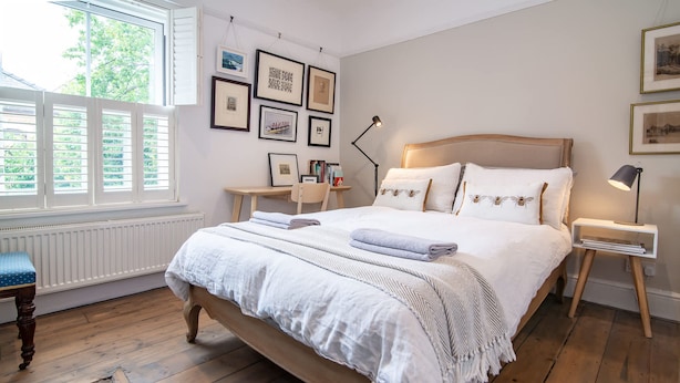 A bedroom with a wooden bed, a desk, and a chair. There are framed pictures on the wall and a window with shutters. - Host Stay Terrace on Canal (Worcester)