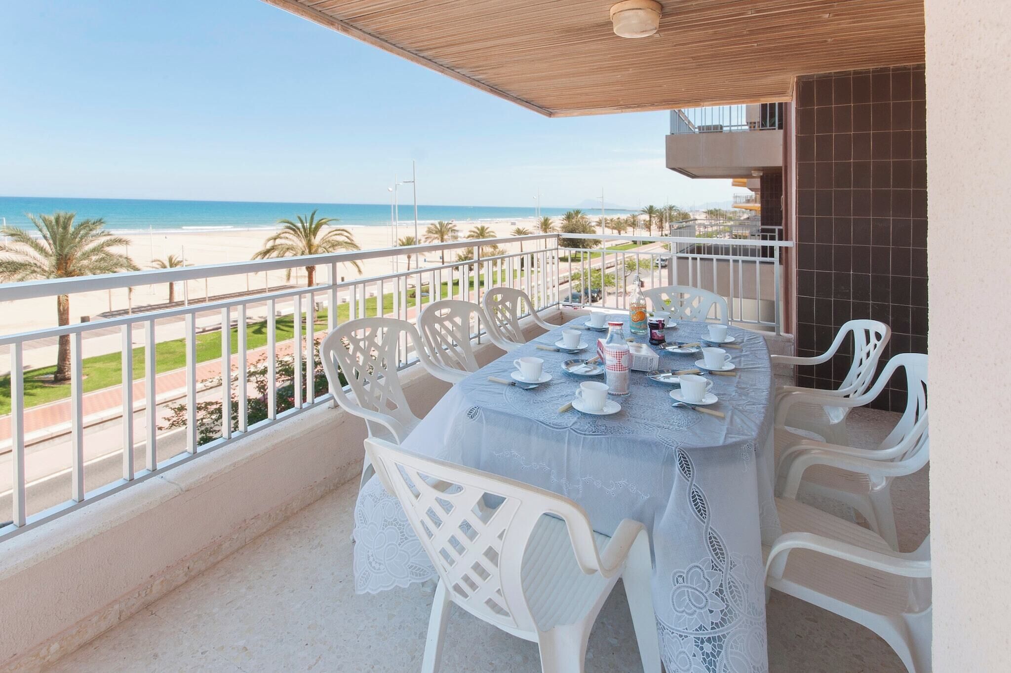 Ein Balkon mit Tisch für zwei Personen, mit Blick auf einen Strand.