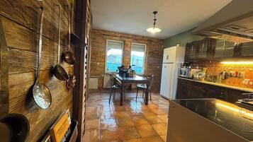 A kitchen with a dining area, wooden walls, and a view of the outside.