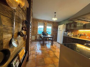 Une cuisine avec un coin repas, des murs en bois et une vue sur l’extérieur.