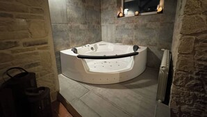 Une salle de bain moderne avec une baignoire sur pieds, des murs en pierre et un miroir encastré.