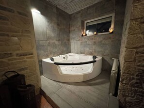 Une salle de bain moderne avec une baignoire sur pieds, des murs en pierre et un miroir encastré.