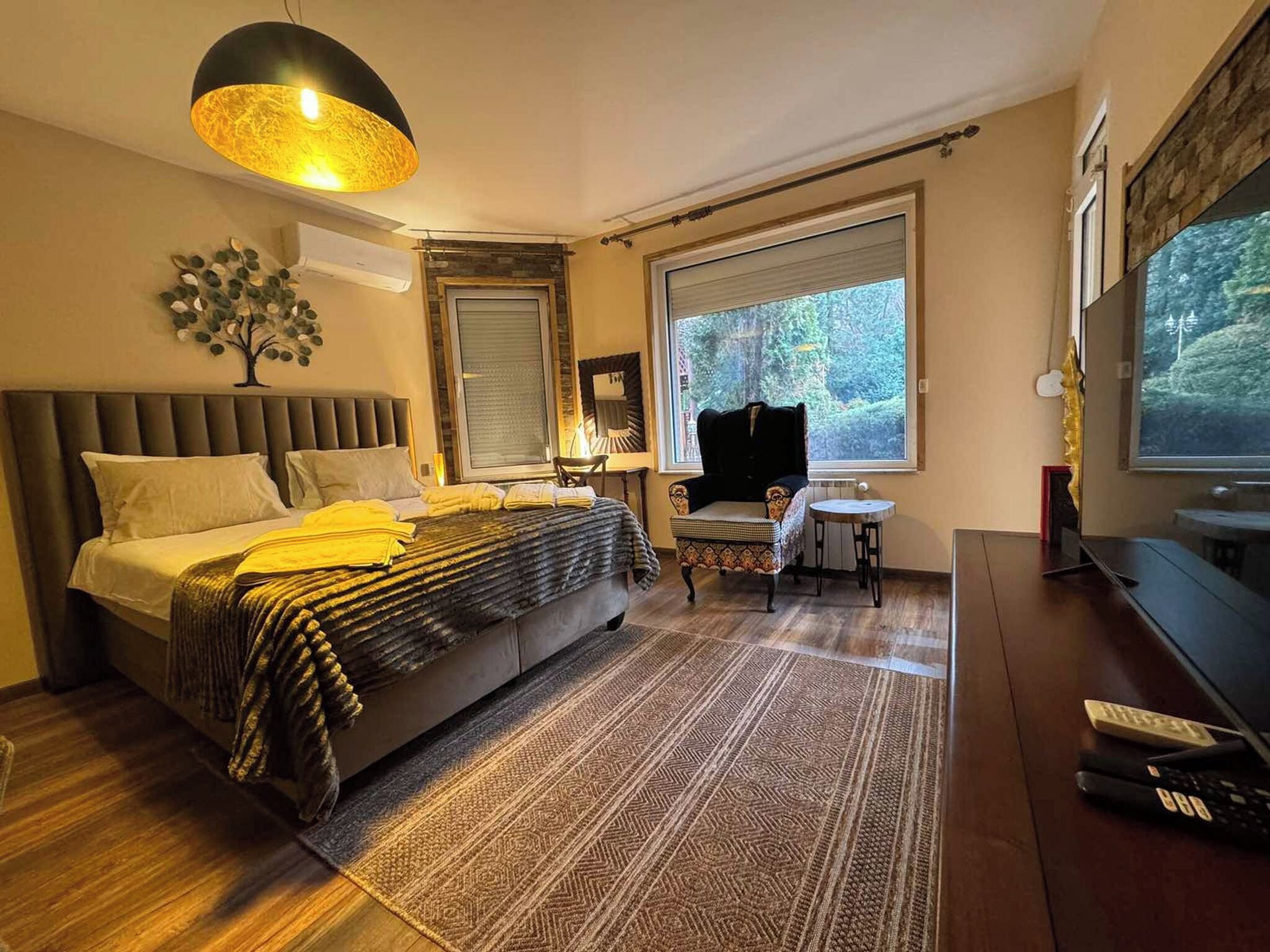 A modern bedroom with a large bed, a small table, a chair, and a TV.