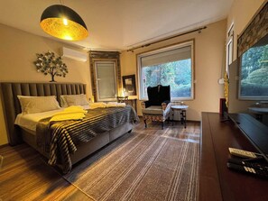 Une chambre moderne avec un grand lit, une petite table, une chaise et un téléviseur.