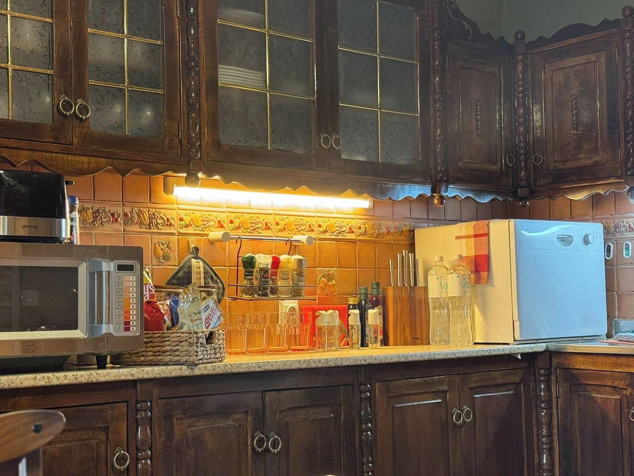 A kitchen with wooden cabinets, a microwave, a refrigerator, and a spice rack.